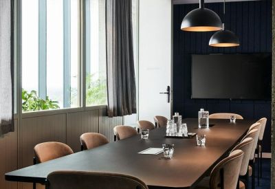 Sophisticated meeting room with a long dark wood table, black pendant lights, and large windows.