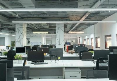 Large open-plan office space with rows of modern white desks and black ergonomic chairs.