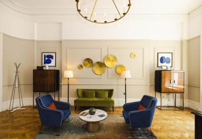Elegant lounge area with velvet green sofa, blue armchairs, and gold wall decor.