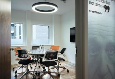 Glass-walled meeting room with a round table and modern circular pendant light.
