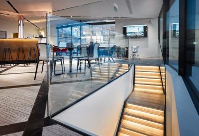 Internal staircase with integrated lighting leading to an upper-level lounge.