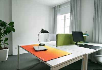 Bright shared workspace with white desks and an orange desk mat.