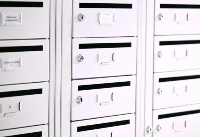 Wall of white secure mailboxes or lockers in a corridor.