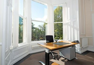 Bright private office featuring a large bay window and wooden desk.