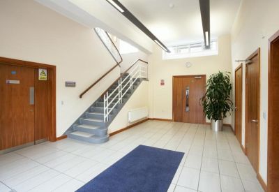Internal lobby area with a grey staircase, wooden doors, and a blue rug.
