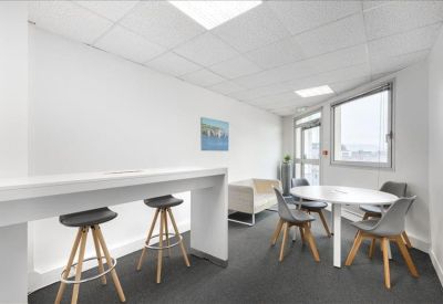 Casual breakout area featuring a white high-top table with stools and a small round meeting table.