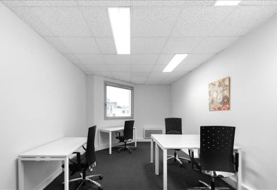 Shared office space with three white desks and black ergonomic chairs.