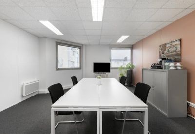 Bright conference room with a long white table, black chairs, and a feature wall in terracotta.