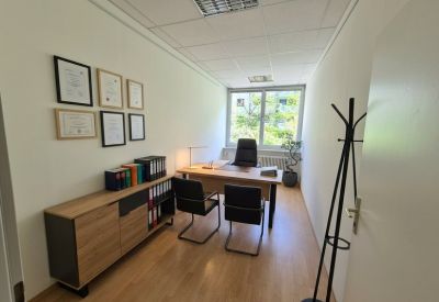 Private office suite with a wooden desk, executive chair, and certificates displayed on the wall.