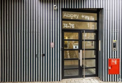Secure entrance with black glass door and building signage.