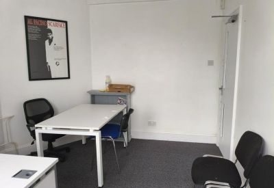Small office suite with a white desk and a movie poster on the wall.