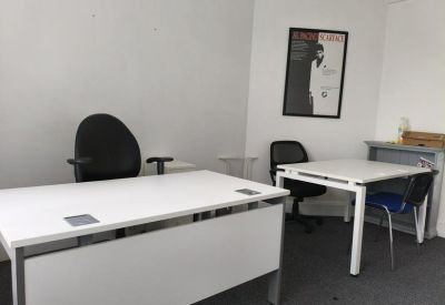 Office room featuring two white desks and a black office chair.