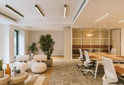 Lounge area with unique rounded white seating, large indoor plants, and bright overhead linear lighting.