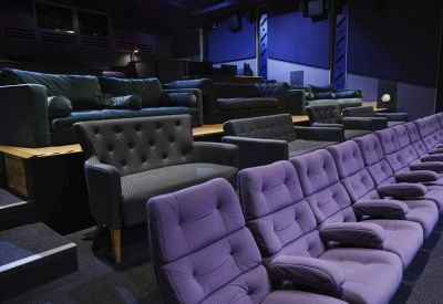 Luxury screening room with a mix of purple theater seats and grey tufted sofas.