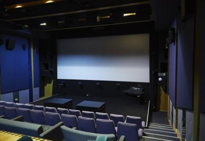 Internal view of a private screening room with a large projector screen and tiered seating.
