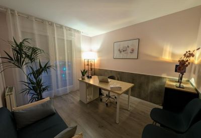 Bright office space with a light wood desk, indoor plant, and framed wall art.