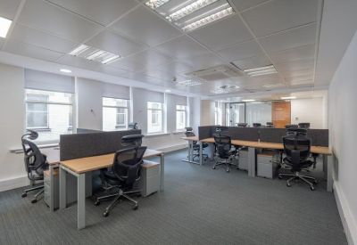 Bright, modern open-plan workspace with rows of ergonomic chairs and large windows.