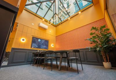 Meeting room with a dark dining table set under a peaked glass skylight.