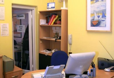 Bright yellow reception area with a wooden desk and computer workstation.