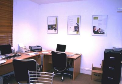 Private office space with wooden desks, black chairs, and wall art.