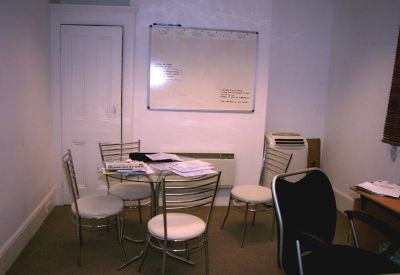 Small meeting room with a glass-topped table and whiteboard.
