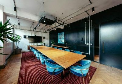 Meeting room with long wooden table and blue chairs.