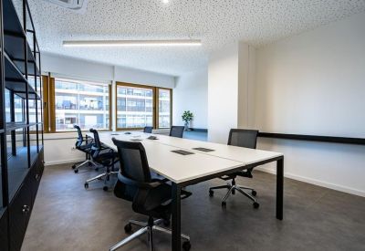 Bright conference room with a long white table, black mesh chairs, and large windows.