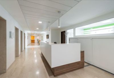 Bright reception area with a white and wood desk and polished floors.
