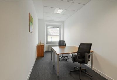 Private two-person office suite with wooden desk and mesh chairs.