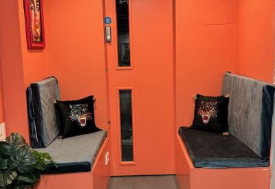 Vibrant orange breakout booth with gray cushioned seating and tiger-themed decorative pillows.