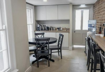 Bright communal kitchen and dining area featuring a round table and exposed brick wall.