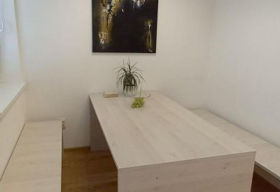Small meeting room with a light wood table, bench seating, and abstract wall art.