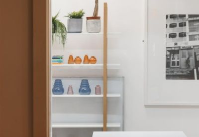 White meeting table in a minimalist room with colorful vases and a framed art piece.