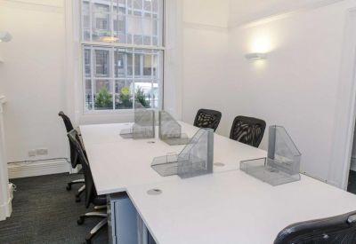 Bright office space with white desks and a large sash window.