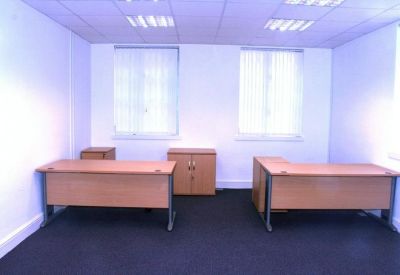 Office space with two desks and natural light from windows.