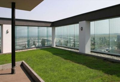 Rooftop terrace featuring a green lawn and glass railings with city views.