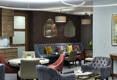 Colorful lounge area with plush seating, patterned pillows, and geometric wall mirrors.