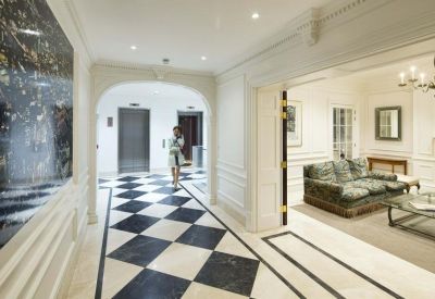 Elegant reception hallway with black and white checkered flooring and an adjacent lounge room.