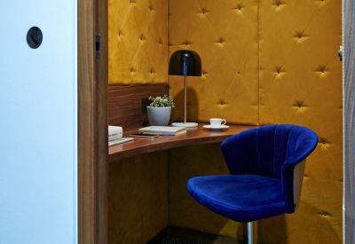 Work pod featuring a blue velvet stool, yellow tufted walls, and a built-in desk.