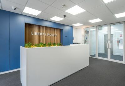 Modern reception area with a white desk, blue feature wall, and wooden accents.