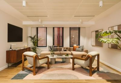 Stylish lounge area with mid-century modern armchairs, a large TV, and a colorful abstract rug.