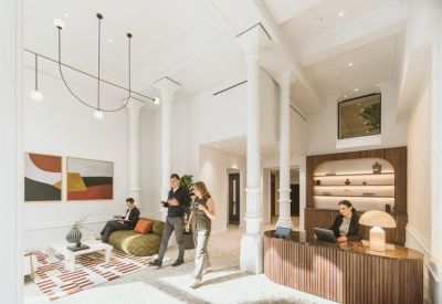 Spacious reception lobby with high ceilings, white pillars, a curved wooden desk, and lounge seating.