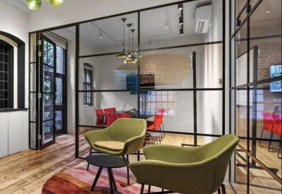 Colorful breakout lounge at 81a, Endell Street with green velvet armchairs and a vibrant circular rug.