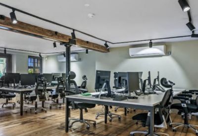 Spacious open-plan office with timber floors and modern workstations under track lighting.