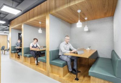 Modern breakout area with private wooden booths and green leather seating.