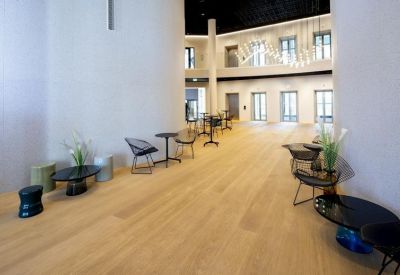 Spacious communal lounge with light wood floors and designer seating.