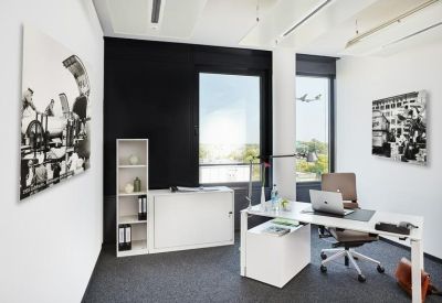 Private office suite with a white desk, ergonomic chair, and large window.