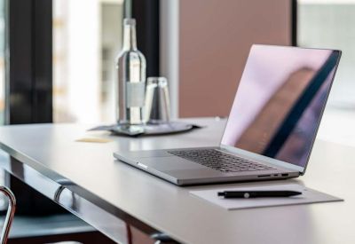 Meeting room at 84, Neue Mainzer Straße with a laptop, water bottle, and pen on a white desk.