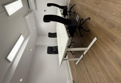 Bright workspace with long white desks and black office chairs.