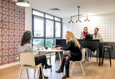 Modern break area with patterned wallpaper and high-top seating.